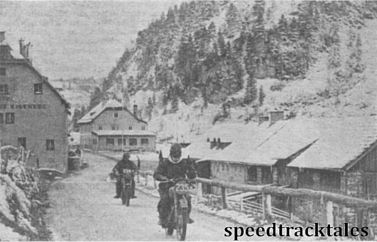 Photo - So this is Austria, in September! The Dutch 499cc BSA rider M.Rodenberg leads Phil Mellers (498 Ariel) through the street of a snow clad village on Saturday. ISDT 1952 (Speedtracktales Collection)